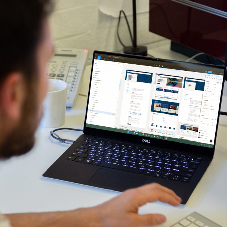 Partial view of person working on laptop displaying outputs focused on a Design system for ABCB