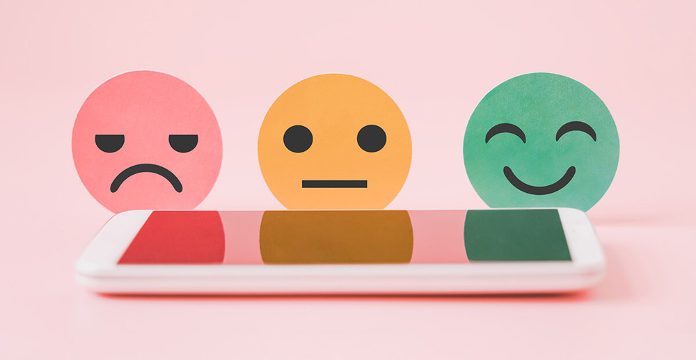 Customer feedback rating options displayed behind a mobile phone, on a pink background.